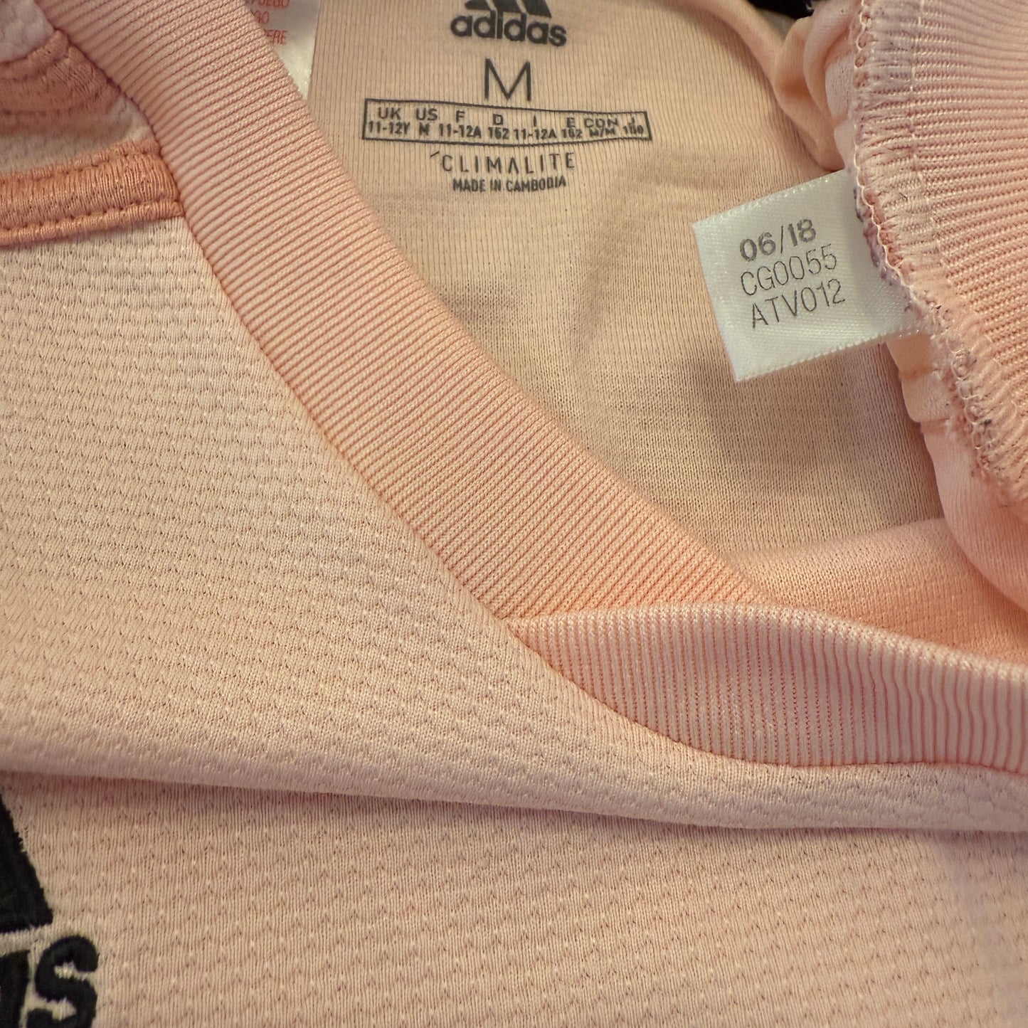 Close-up of a pink Adidas garment with a tag showing the code CG0055.
