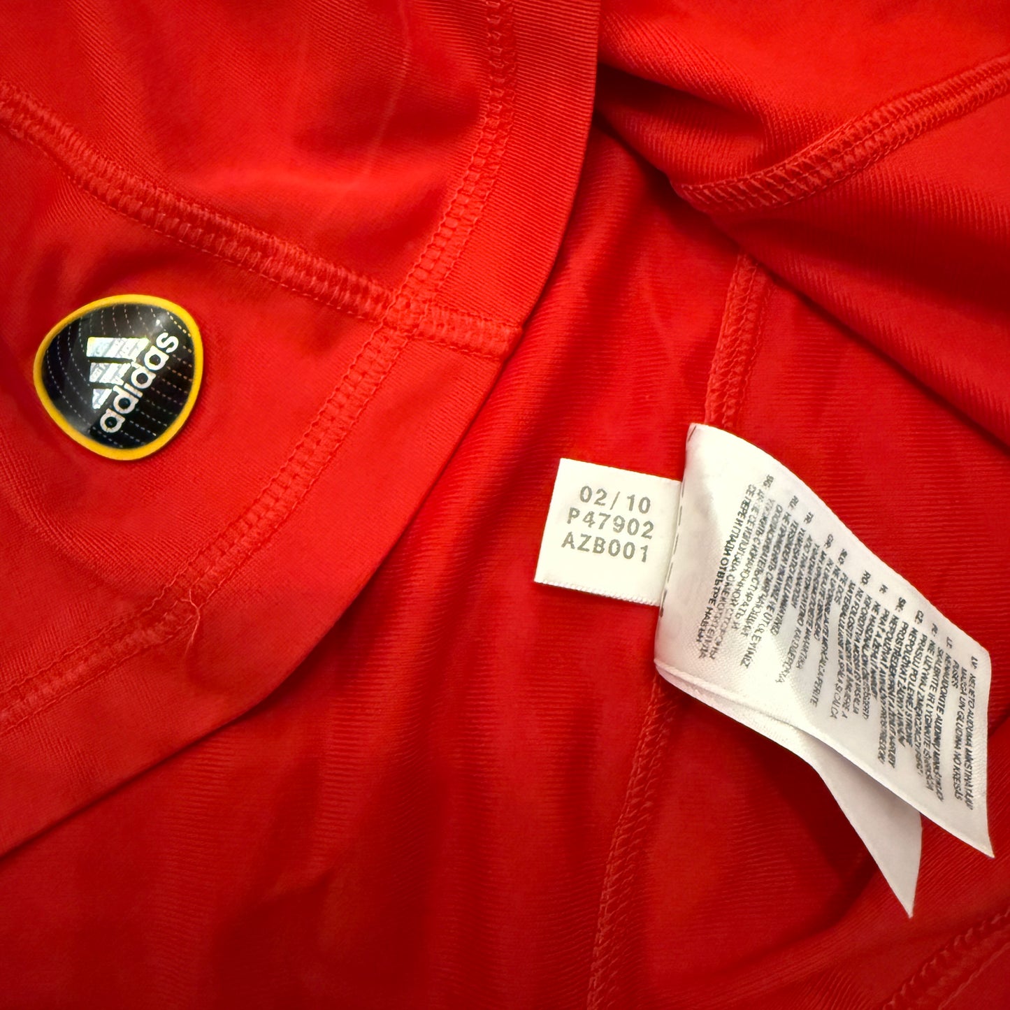 Close-up of a red shirt with an Adidas logo and tag code P47902 for the Spain 2010 Home Shirt