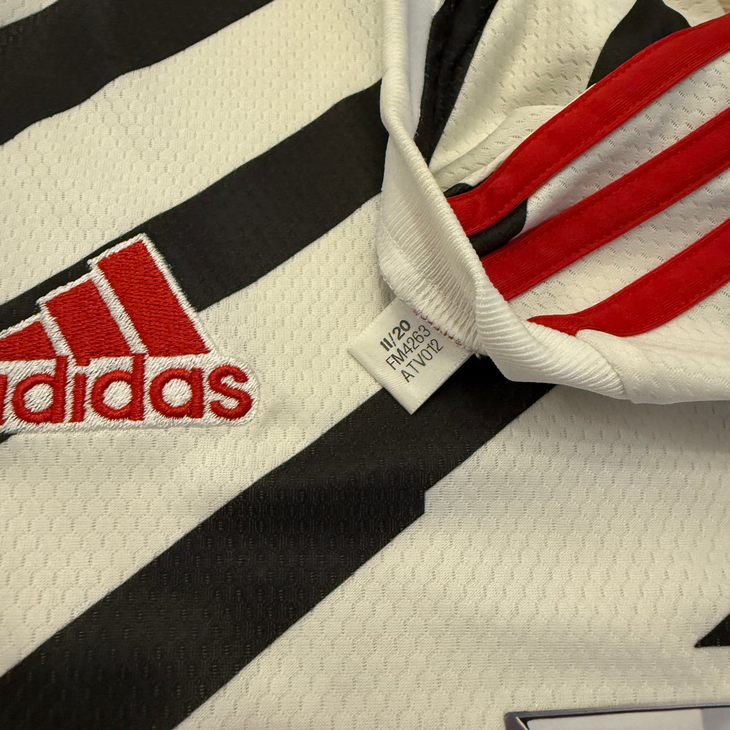 Close-up of Adidas logo on a sports jersey with a tag FM4263.