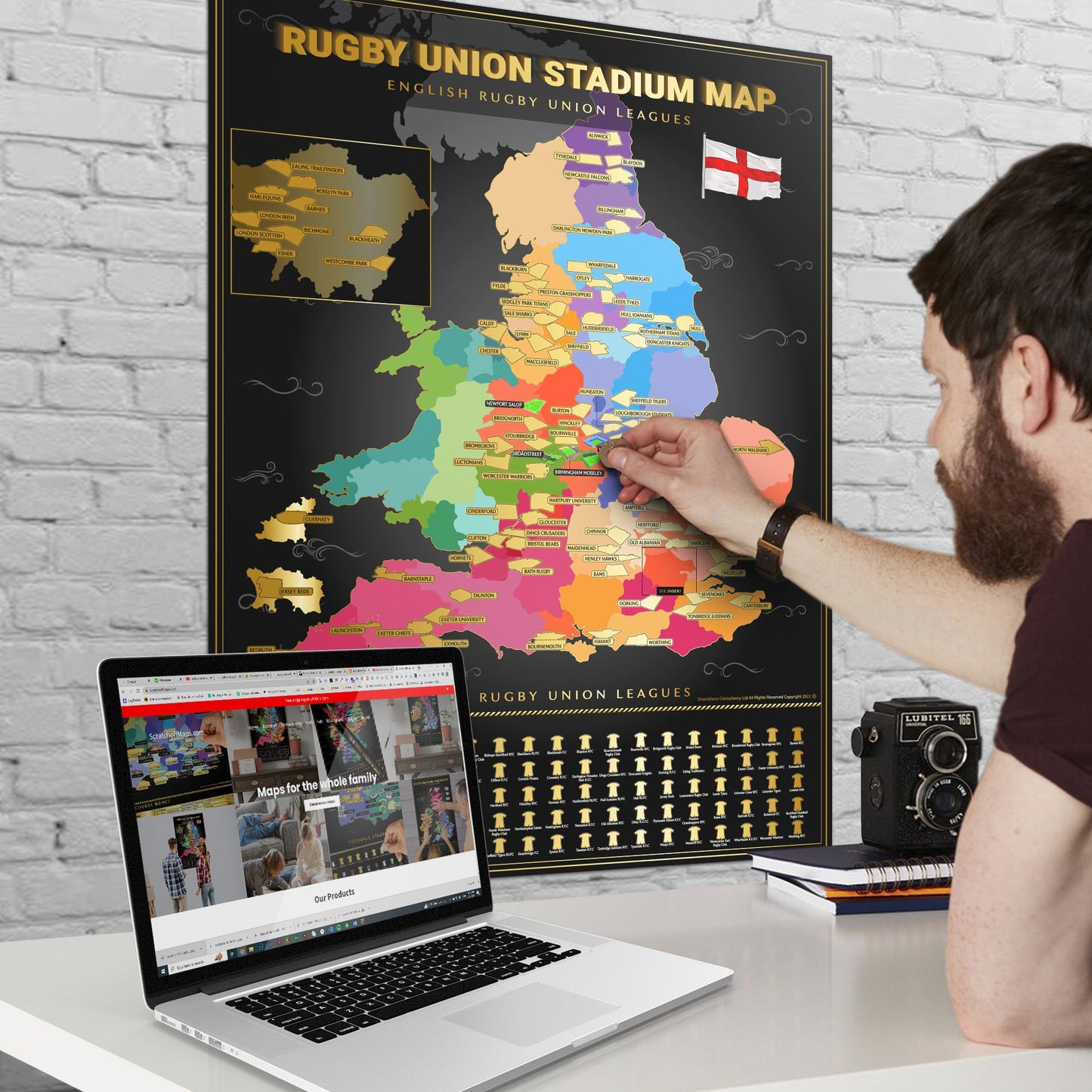 Person interacting with a colorful rugby stadium map on a desk with a laptop.