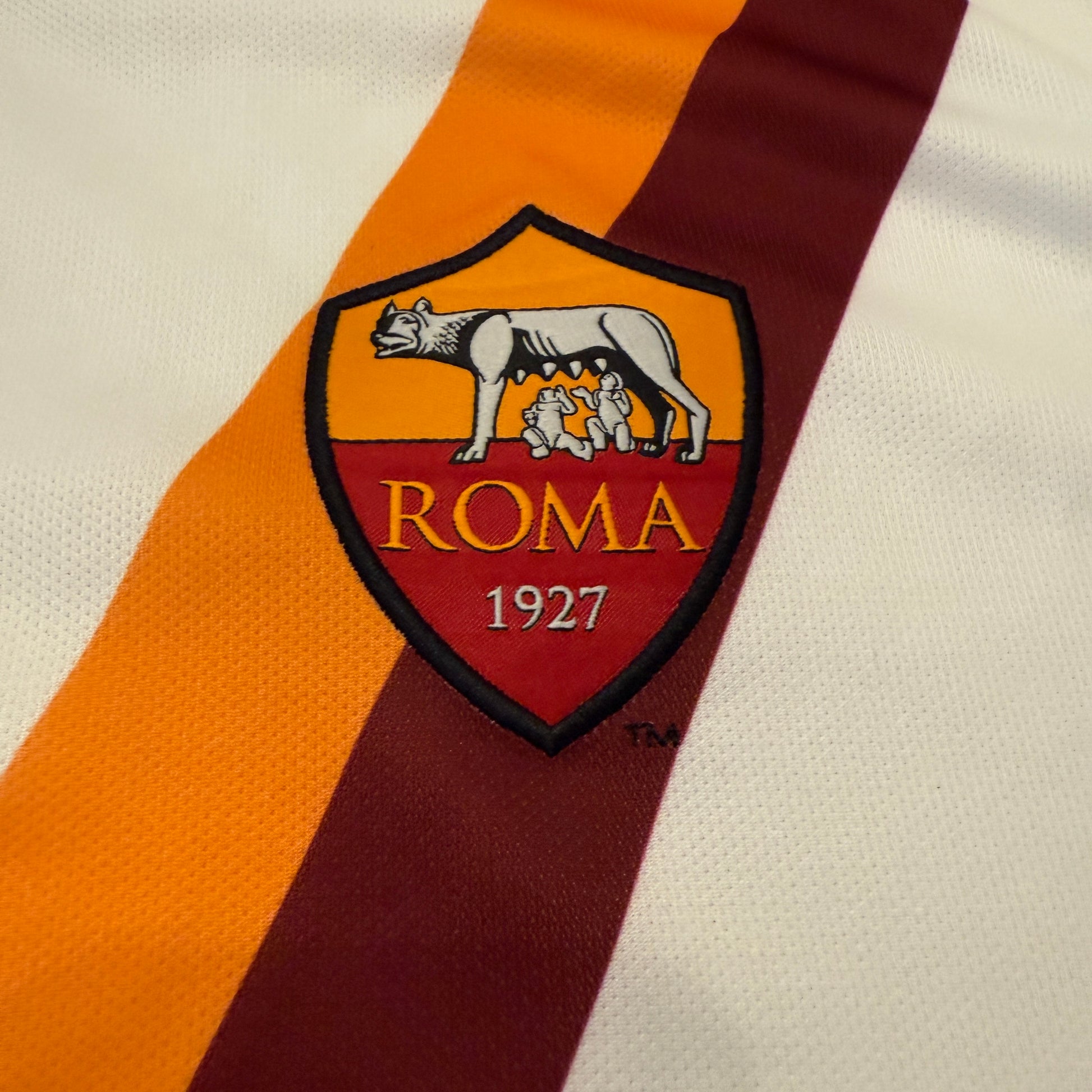 Close-up of the 2014 Roma logo with 'Roma' and '1927' on a striped background