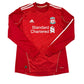 Red sports jersey with Standard Chartered branding on a white background. The Liverpool FC home shirt in the 2010/2011 and 2011/2012 seasons