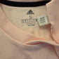 Close-up of Adidas label code CG0038 on a pink garment with visible text and logo.