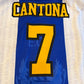 Blue sports jersey with 'CANTONA' and number '7' in yellow on a blurred background.