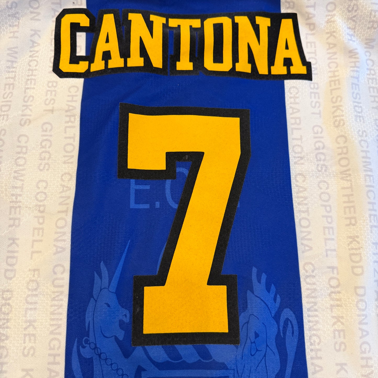 Blue sports jersey with 'CANTONA' and number '7' in yellow on a blurred background.