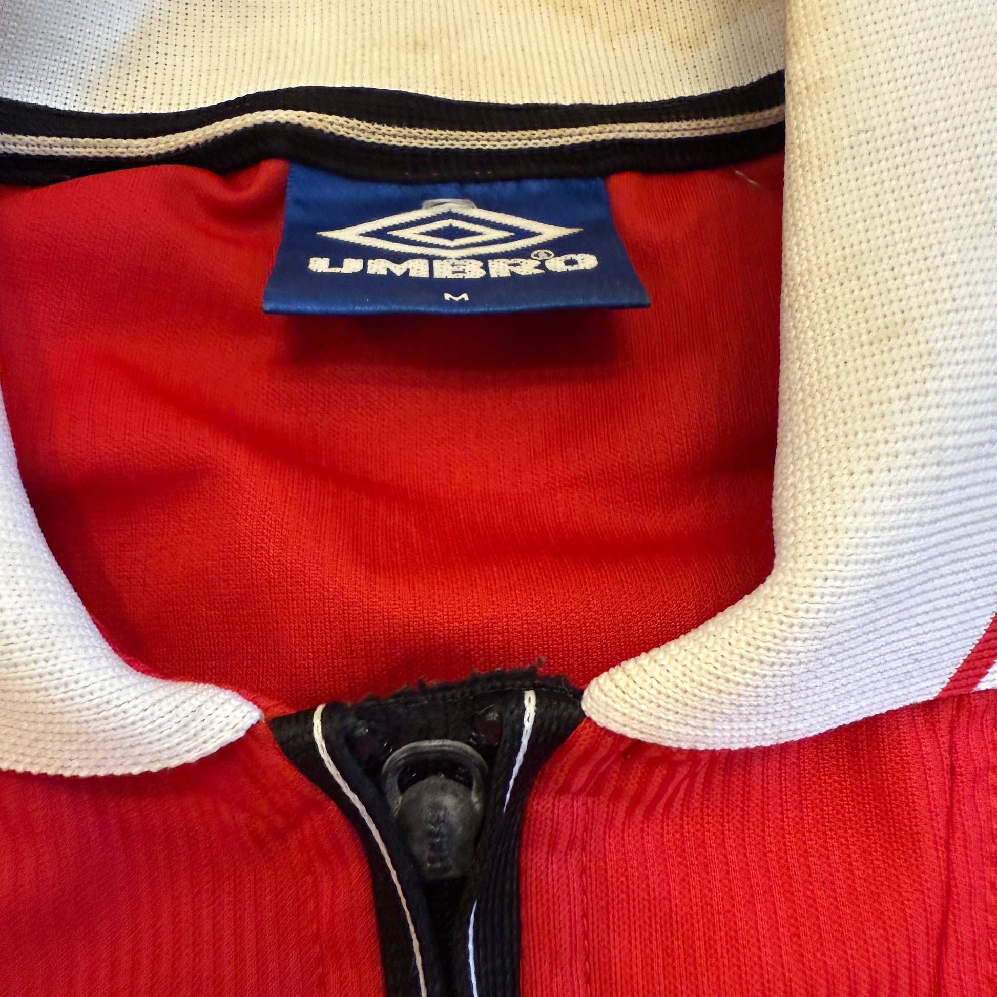 Close-up of a red sports shirt with an Umbro label.