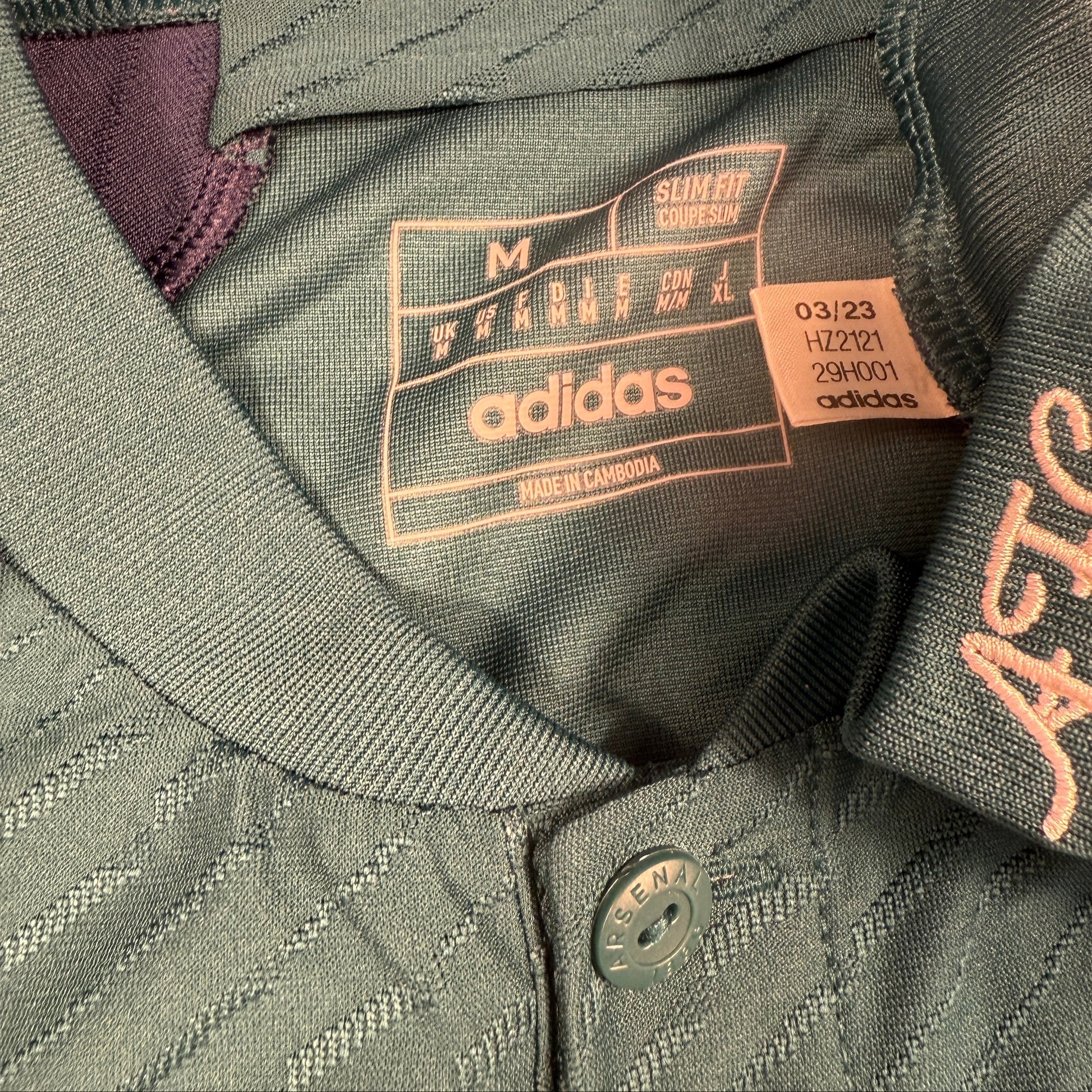 Close-up of an Adidas jacket with brand label showing code HZ2121 and logo.