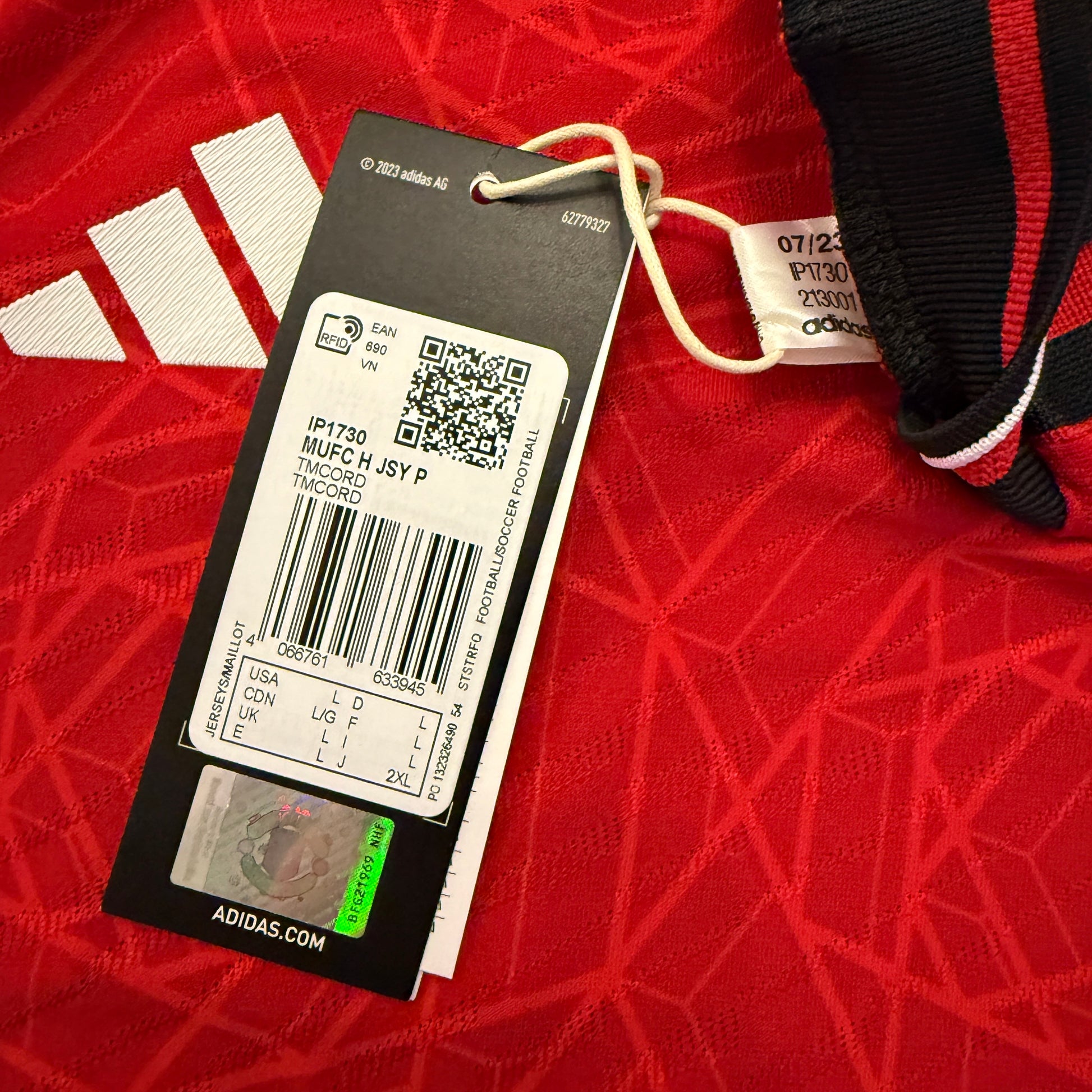 Adidas tag IP1730 on a red textured surface