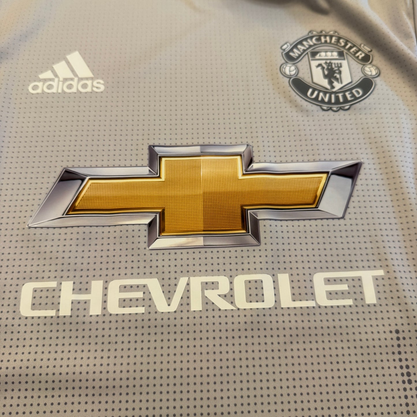 Close-up of a sports jersey with Chevrolet, Adidas, and Manchester United logos.