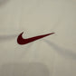 Close-up of a maroon Nike logo on beige fabric