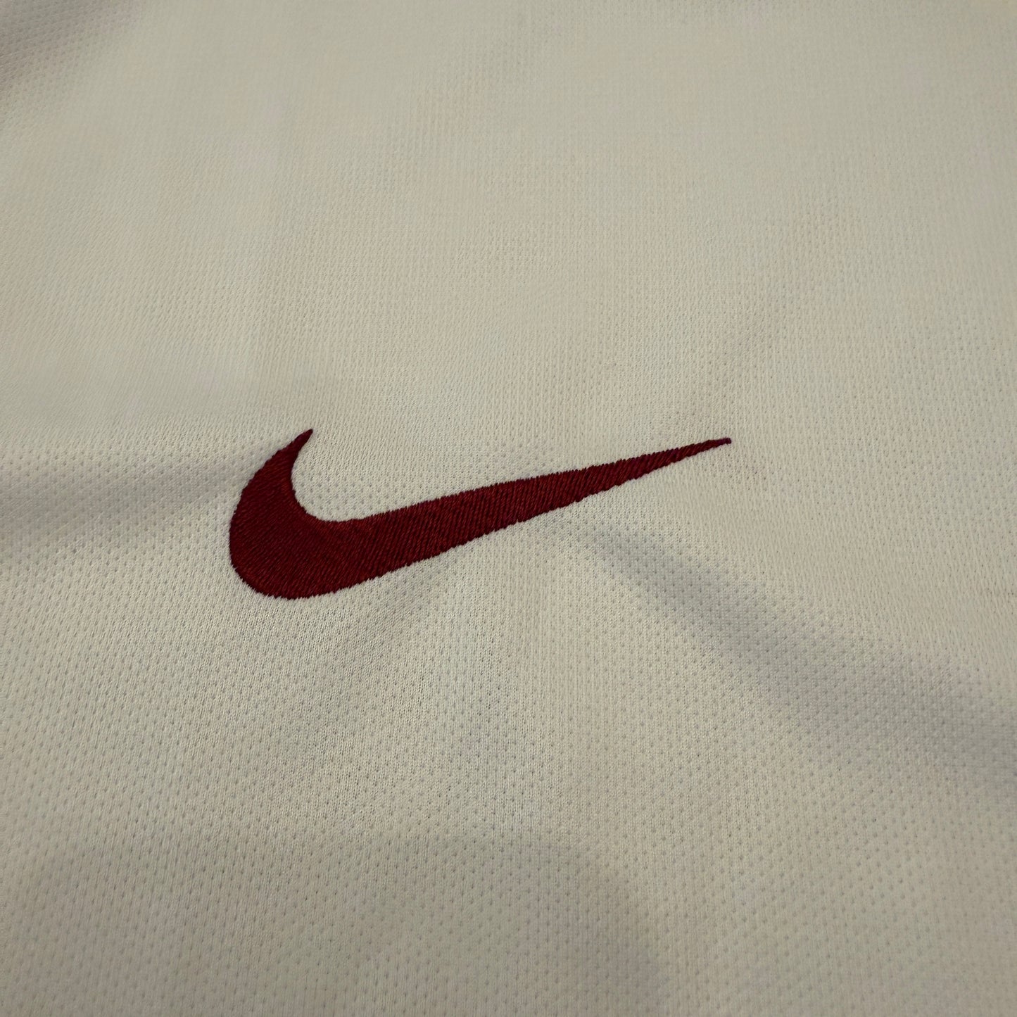 Close-up of a maroon Nike logo on beige fabric