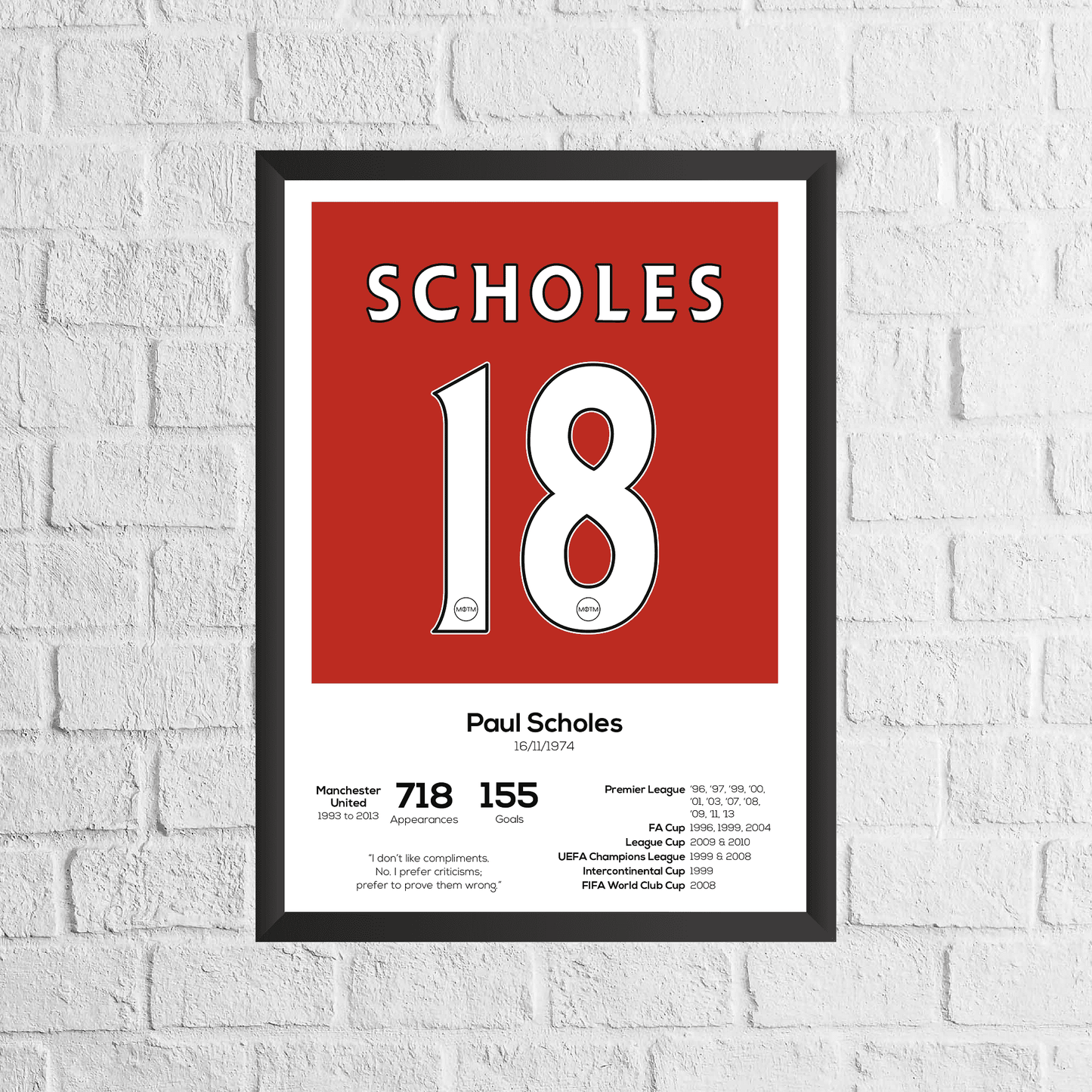 Framed poster with 'Scholes 18' on a red background against a white brick wall.