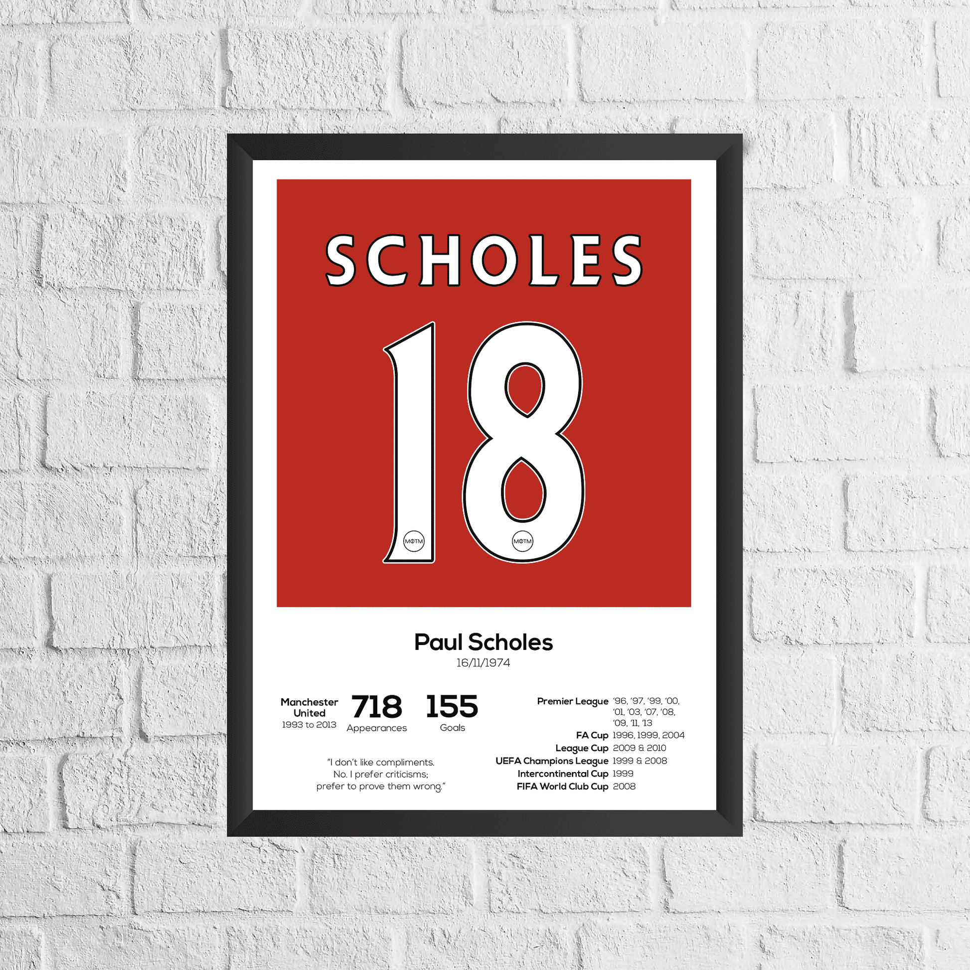 Framed poster with 'Scholes 18' on a red background against a white brick wall.