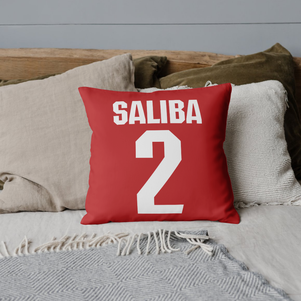 Saliba 2 Arsenal Font Style Cushion Cover on a bed with other cushions